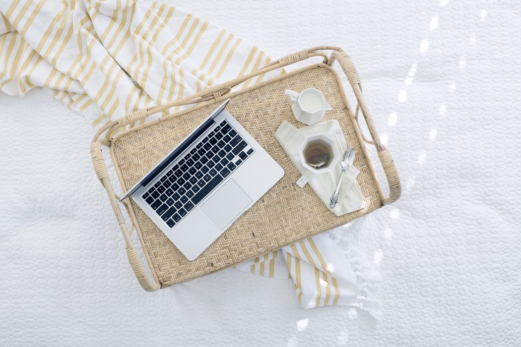 A tray with laptop, coffee, sugar, and a spoon.